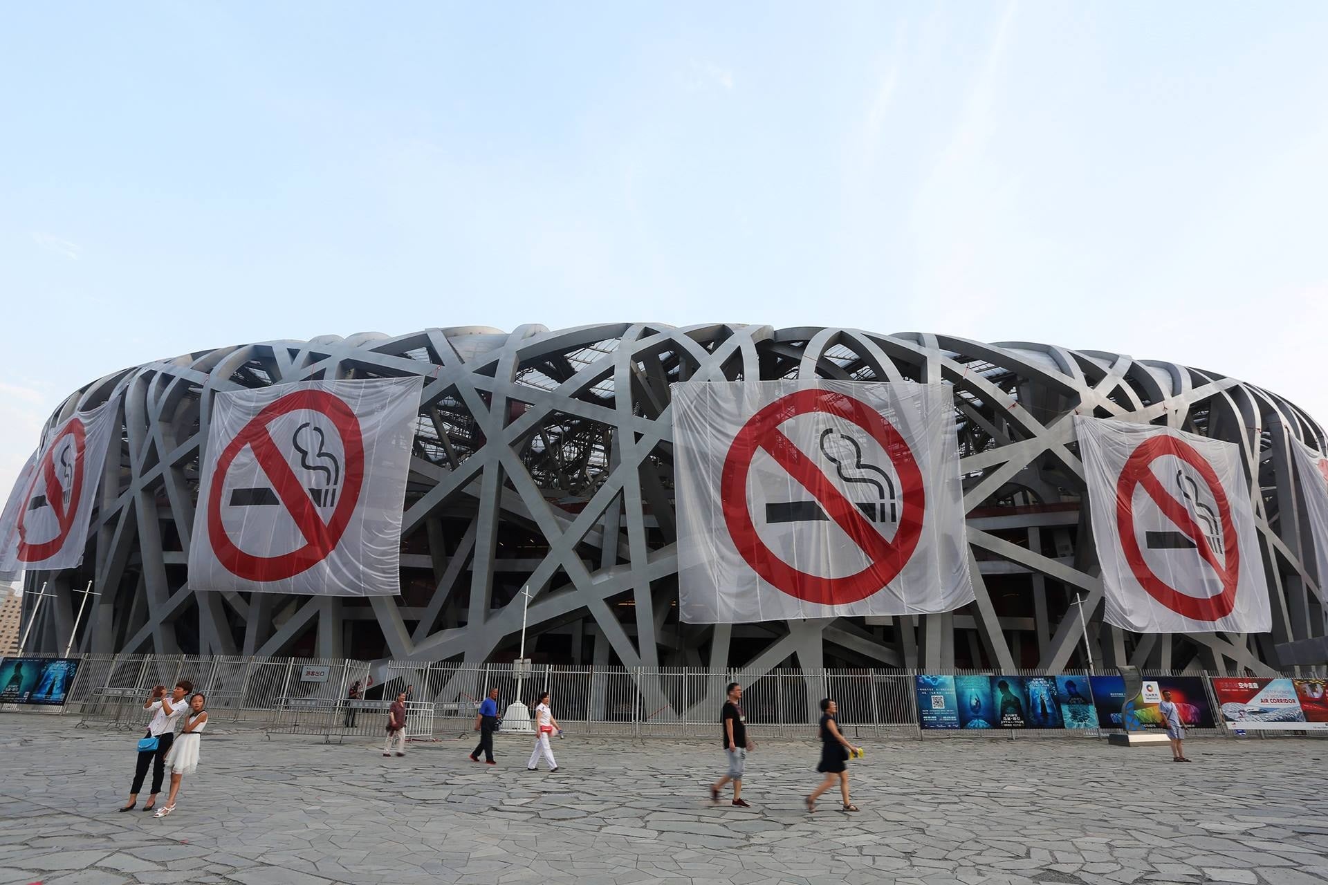 No smoking banners on a large building shaped like a bird's nest in China